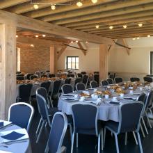 Feestzaal met ronde tafels en houten balken bij Bouwelhoeve